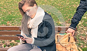 Pickpocketing from the bag of a young woman in a park