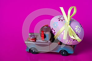 Pickup toy carrying one decorated easter egg on a pink background