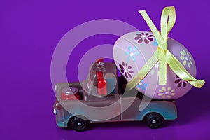 Pickup toy carrying one decorated easter egg on a violet background
