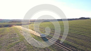 Pickup truck driving along road near field with sunlight at background. Black car moving on route at countryside. Off