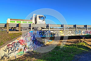 Pickup truck speeds by on a graffiti covered bridge