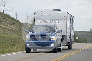 A pickup truck towing a camper RV trailer during summer time on the route