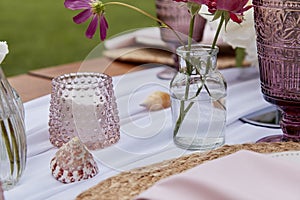 Picnic aesthetics table setting, flowers arrangement, shells close up. Cozy setup with flowers and candles