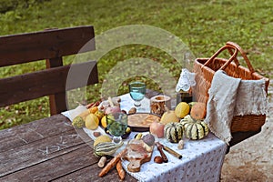 picnic in autumn park. Food, drinks, picnic basket on a wooden table in the garden. Cozy lunch atmosphere.