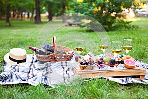 Picnic background with white wine and summer fruits on green grass, summertime party