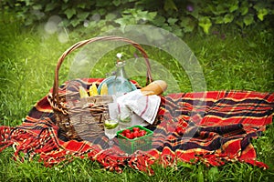 Picnic basket with berries, lemonade, corn and bread.