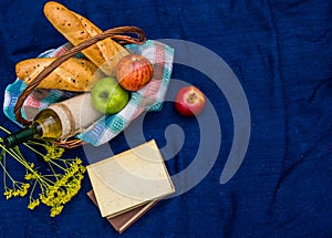 Picnic basket on the blue carpet top view. Books, yellow flowers