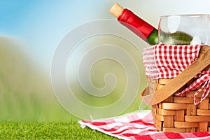 Picnic basket with a bottle of red wine and glasses on a wooden table with a tablecloth. relaxing on a picnic, and enjoyable in