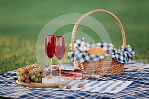Picnic basket with drinks, food and fruit on green grass outside in summer park
