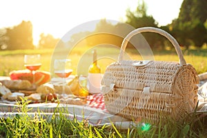 Picnic basket, food and drinks on blanket outdoors