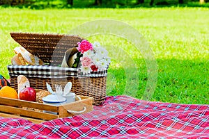 Picnic basket has a lot of food on green grass.