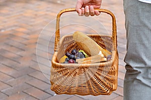 A picnic basket with the ingredients for a lunch in the open air. A man is holding a picnic basket