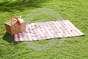 Picnic basket with a red and white tablecloth on the green lawn