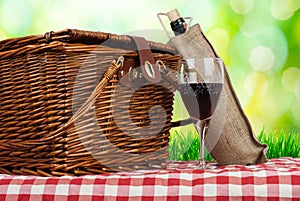 Picnic basket on the table with glass of wine and bottle
