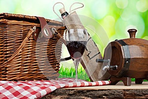 Picnic basket on the table with glass of wine and tun