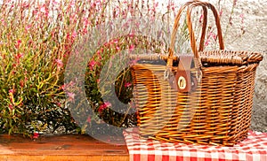 Picnic basket on the table with red flowers