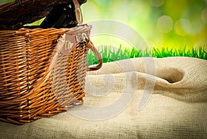 Picnic basket and wine botle on the table with sack cloth