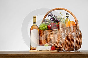 Picnic basket with wine and products on wooden table against white background