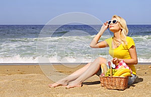Picnic on the Beach. Blonde Young Woman with Basket of Food