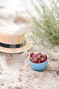 Picnic on beach, cherries in blue plate, straw hat on background