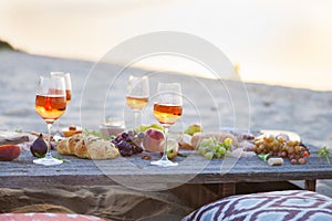 Picnic on the beach at sunset in boho style, food and drink conc