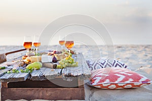 Picnic on the beach at sunset in boho style, food and drink conc