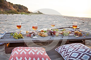 Picnic on the beach at sunset in boho style, food and drink conc