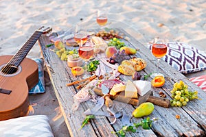 Picnic on beach at sunset in boho style. Romantic dinner, friend