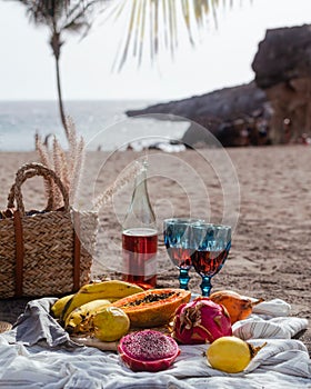 Picnic on the beach on the sunset with rose wine and fresh fruits