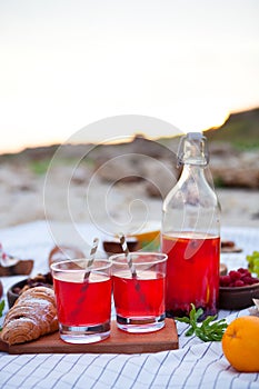 Picnic on the beach at sunset in the white plaid, food and drink