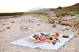 Picnic on the beach at sunset in the white plaid, food and drink