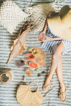 Picnic concept with woman in dress, wine, fruits and baguette
