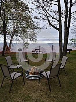 Picnic firewood relax chairs fire pit Sandy beach Lake water horizon Birch tree trunk branches white