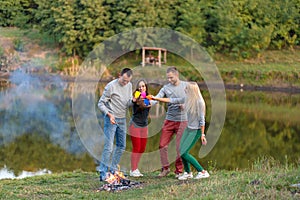 Picnic with friends in at lake near bonfire. Company friends having hike picnic nature background. Hikers relaxing during drink