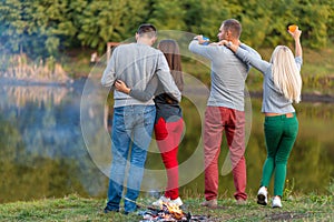 Picnic with friends in at lake near bonfire. Company friends having hike picnic nature background. Hikers relaxing during drink