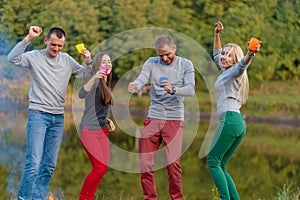 Picnic with friends in at lake near bonfire. Company friends having hike picnic nature background. Hikers relaxing during drink