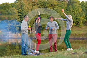 Picnic with friends in at lake near bonfire. Company friends having hike picnic nature background. Hikers relaxing during drink