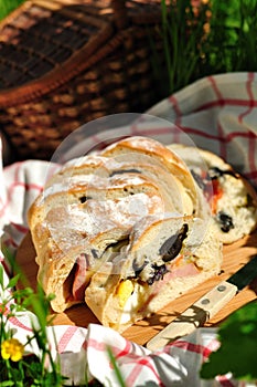 Picnic loaf stuffed with ham, black olives, tomato, egg, pickles and basil