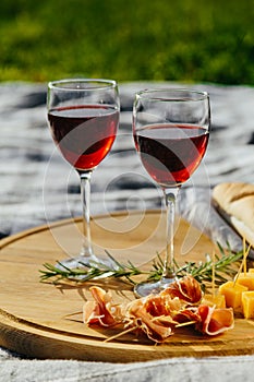 picnic in nature a light meal under wine, on a wooden background two glasses of red wine