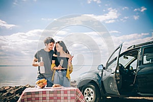 Picnic near the water. Happy family on a road trip in their car. Man and woman are traveling by the sea or the ocean or