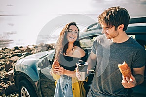 Picnic near the water. Happy family on a road trip in their car. Man and woman are traveling by the sea or the ocean or