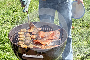 Picnic outdoors in the summer. Cooking on a round grill fish sea bass and zucchini slices