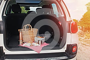 Picnic Package and Basket with Croissant and Sandwiches Lies on the on the Trunk of Car
