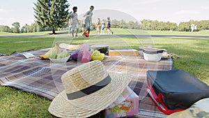 Picnic in the park, litter, fruits, lunch, children playing football in the background