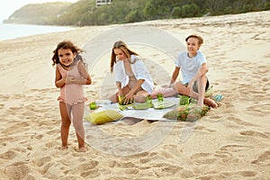 Picnic. Portrait Of Family On Beach Having Lunch. Mother With Kids Enjoying Weekend At Tropical Ocean.