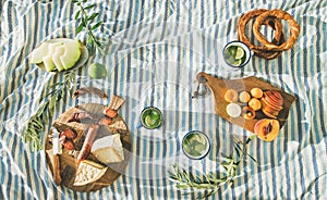 Picnic set with fruit, cheese, toast, honey, wine with a wicker basket and a blanket. Beautiful summer background with