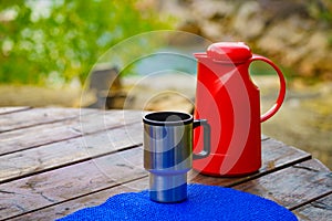 Picnic site table with thermos and thermal mug, photo