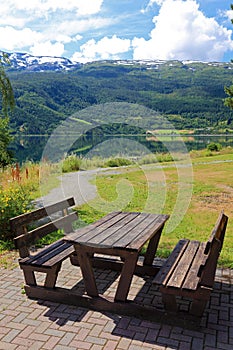 Picnic table and benches near lake.