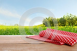 Picnic table with checkered red napkin and picturesque landscape on background