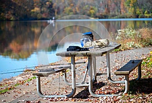 Picnic table with fishing gear and two rods boaters in background lake